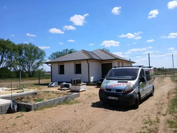 Elkészült kontyolt cseréptetős családi ház céges furgonnal, kék ég
